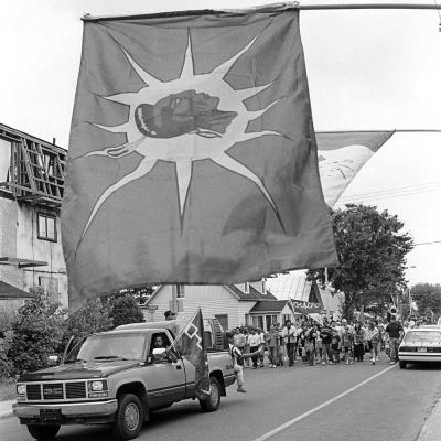 Back view of marching crowd holding Mohawk Warrior Society and Hiawatha Belt Flags on Kanesatake, July 11, 1995 (Quebec).